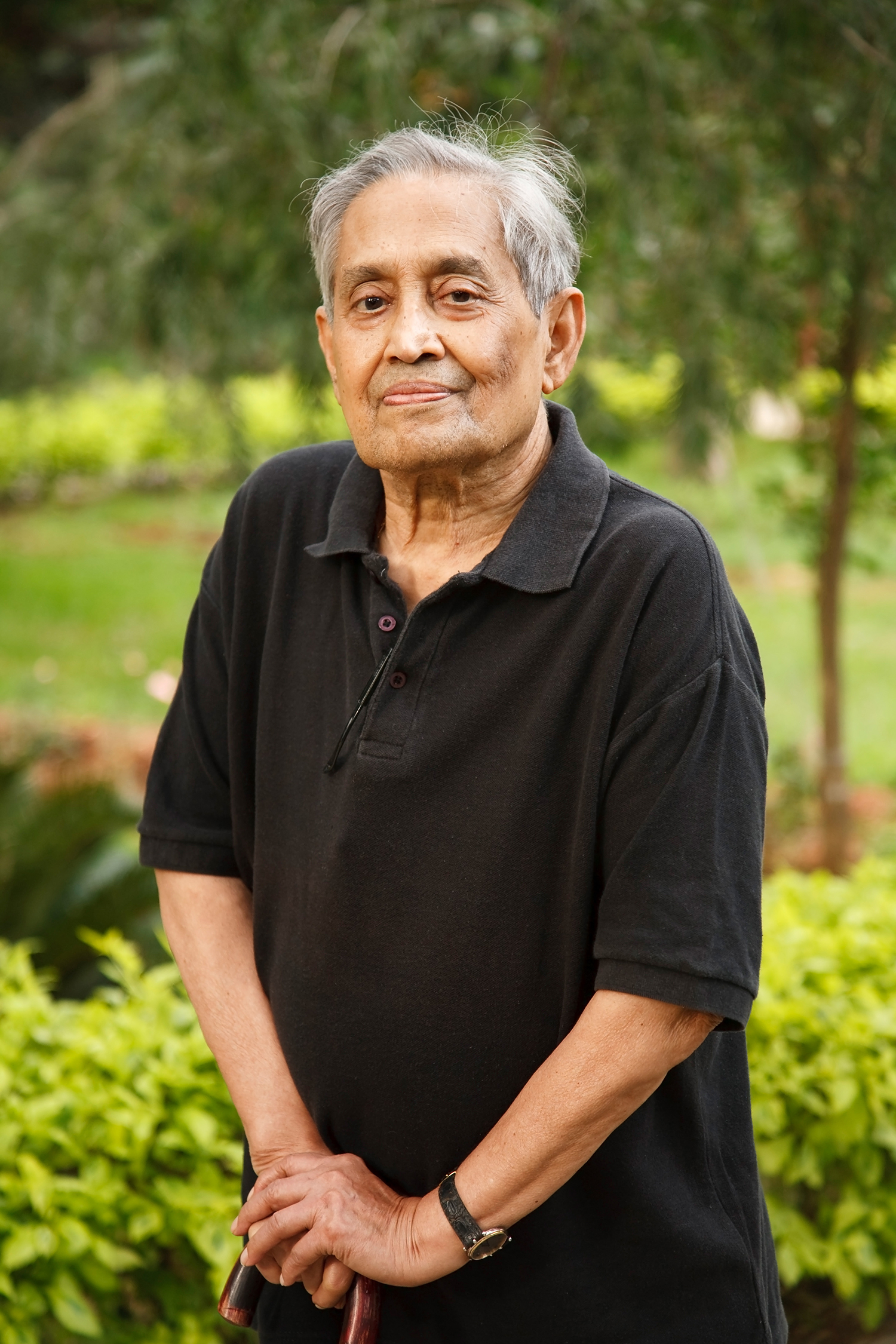 Senior man standing with a cane, wearing a black shirt