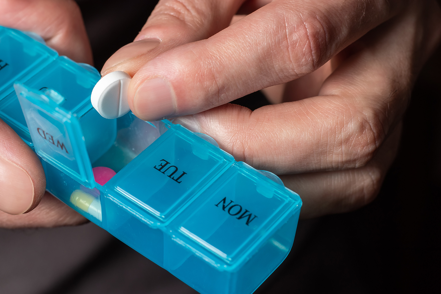 Man taking pills from a pill organizer